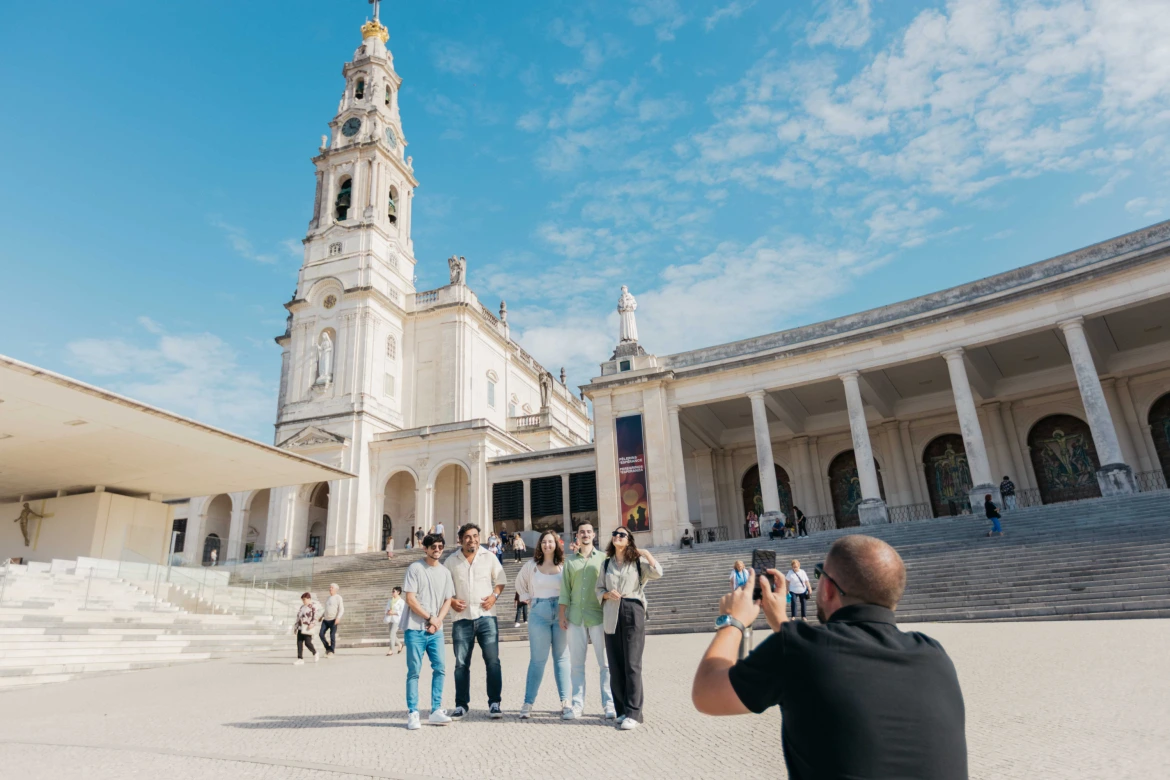 group of tourists visiting Fátima sanctuary with a tour guide and taking a photo of the moment