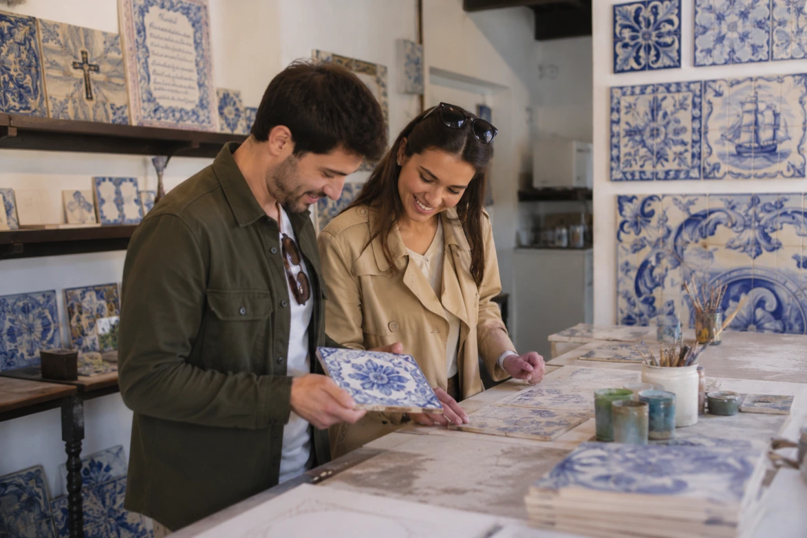 Visitantes a explorar uma oficina tradicional de azulejos portugueses com peças artesanais durante uma visita guiada em Lisboa