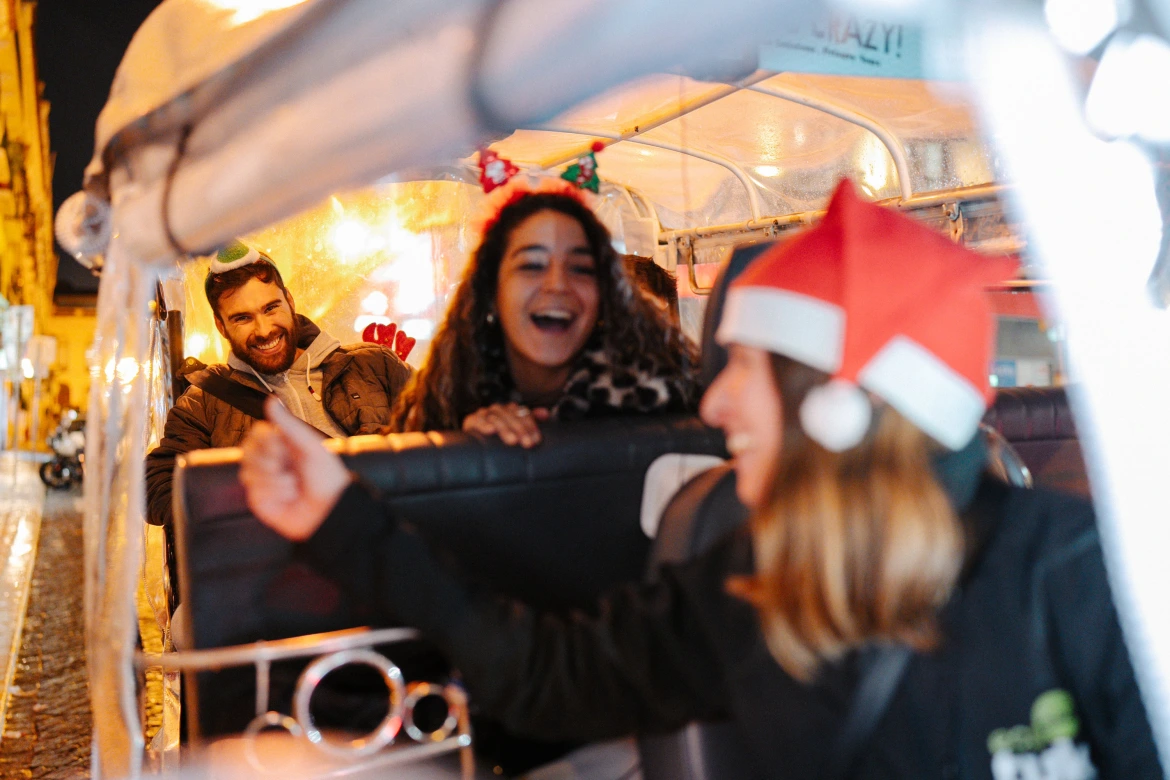 Viajantes a explorar as iluminações de Natal de Lisboa num passeio privado de tuk tuk elétrico com decoração festiva