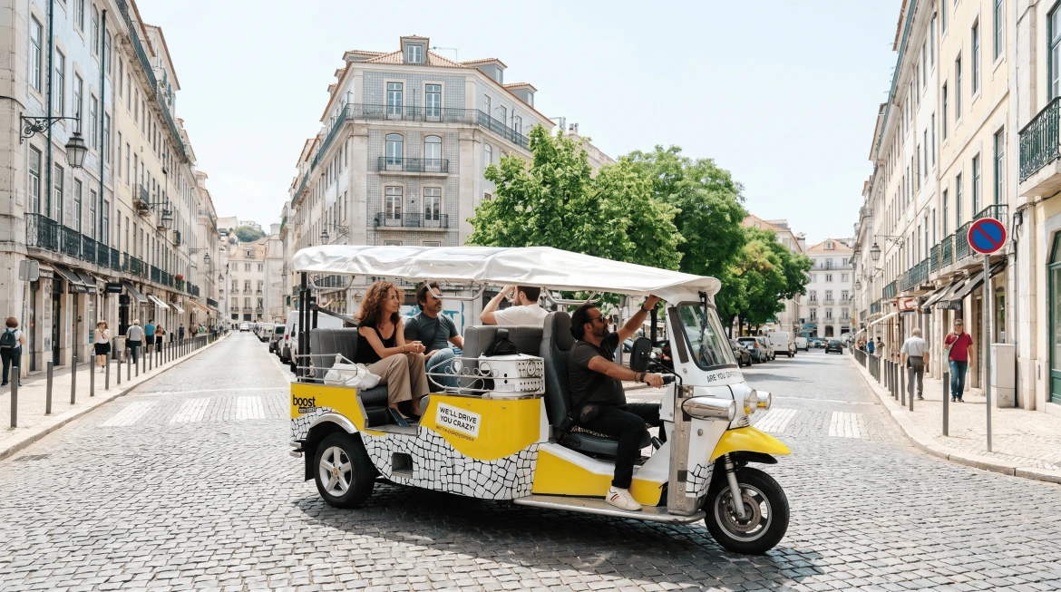 Viajantes a desfrutar de um passeio guiado de tuk tuk elétrico pelos bairros históricos e monumentos icónicos de Lisboa