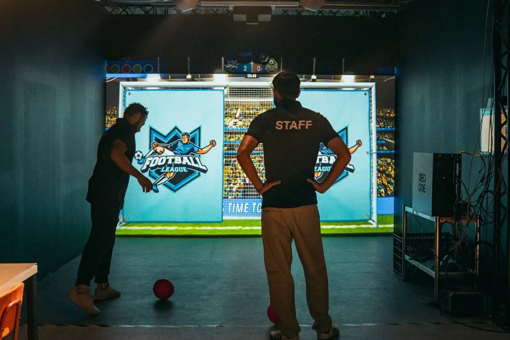 Players taking part in an interactive football challenge projected on The Level Wall at Level Arena.