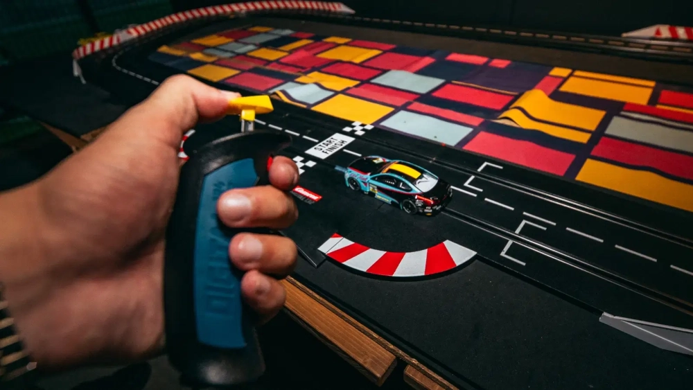 Player controlling a miniature racing car around a tabletop track during a gaming challenge at Level Arena.