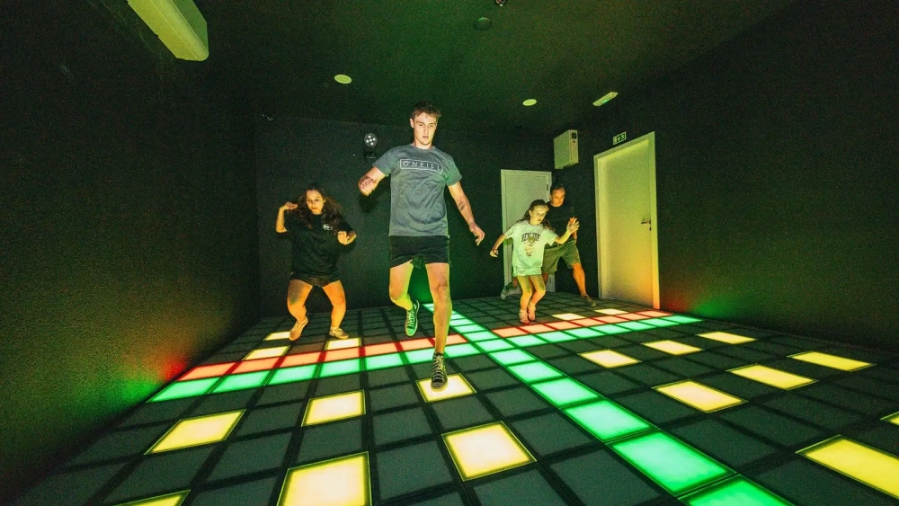 Group completing an interactive challenge using wall-mounted game stations inside Level Arena.