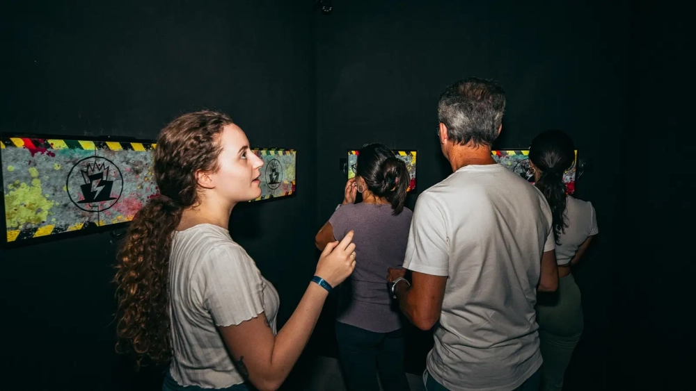 Group completing an interactive challenge using wall-mounted game stations inside Level Arena.