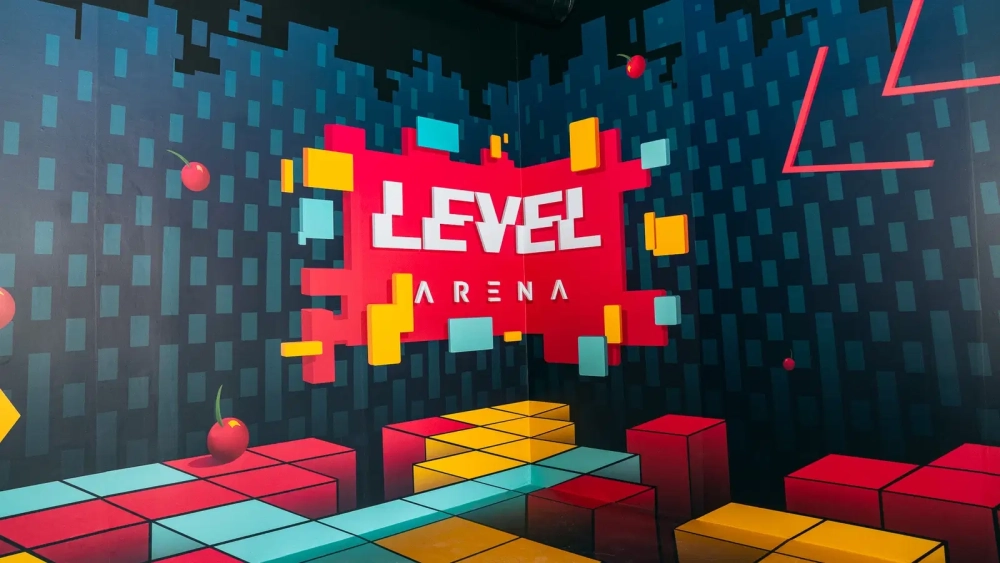 Colourful Level Arena interior with the venue logo surrounded by geometric gaming-inspired decorations.
