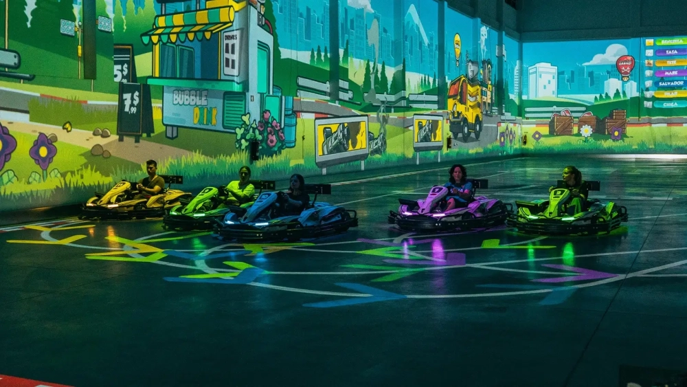 Players driving electric BattleKarts across an augmented reality track projected inside Level Arena near Lisbon.