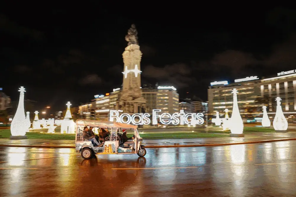 Tuk tuk passing Christmas lights at Marquês de Pombal in Lisbon at night