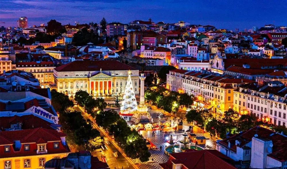 Rossio Square in Lisbon illuminated at Christmas with a festive tree beside the D. Pedro IV monument