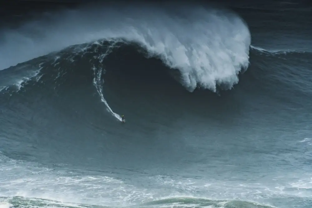 Surfista numa onda gigante do Atlântico na Nazaré, um dos locais mais conhecidos do mundo para surf de ondas grandes.