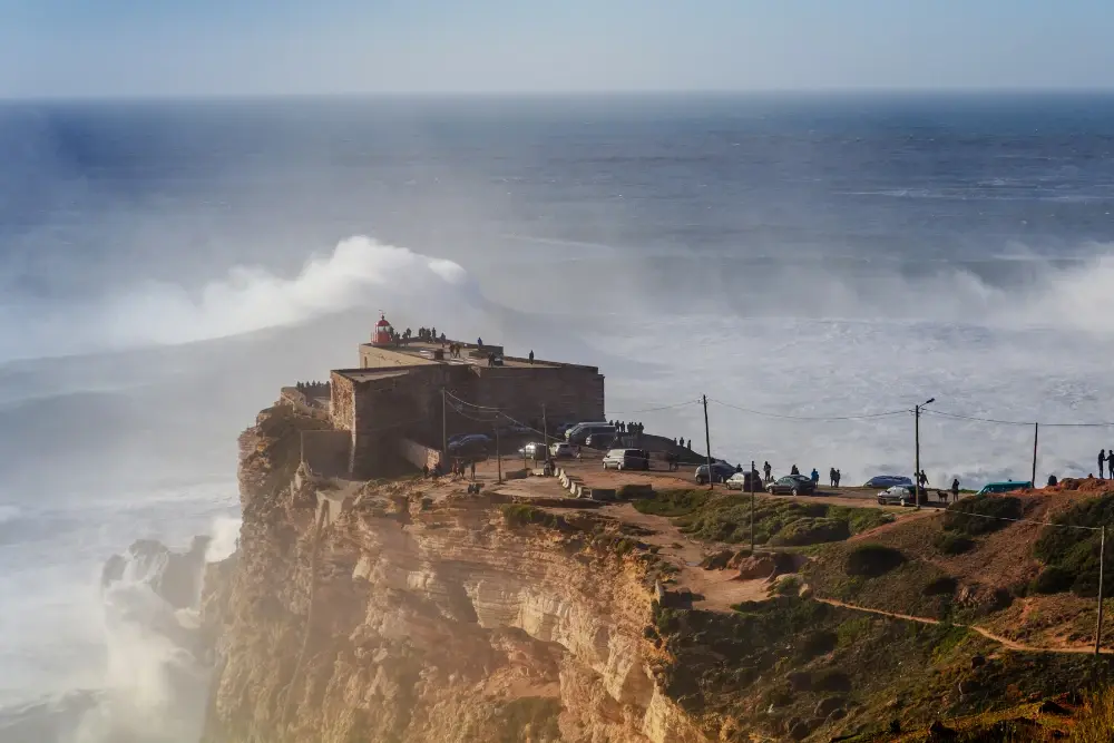 Forte de São Miguel Arcanjo nas falésias da Nazaré, com grandes ondas do Atlântico a rebentar junto à Praia do Norte.