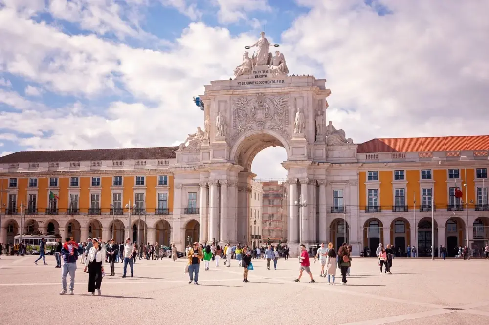 Praça do Comércio in Lisbon with the Rua Augusta Arch and surrounding historic yellow buildings.