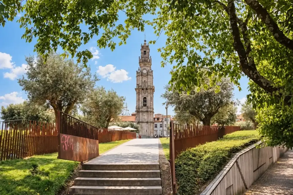 View of Torre dos Clérigos in Porto, framed by trees and a pathway leading toward the historic bell tower.
