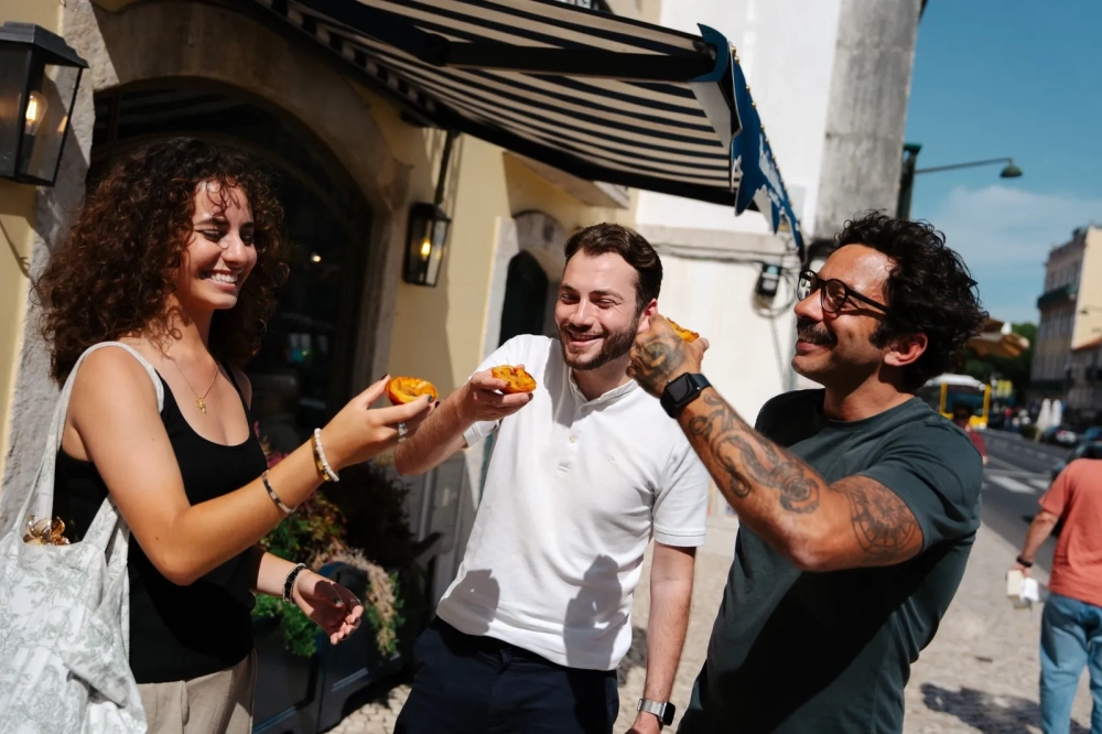 Travellers enjoying pastéis de nata outside a bakery in Lisbon